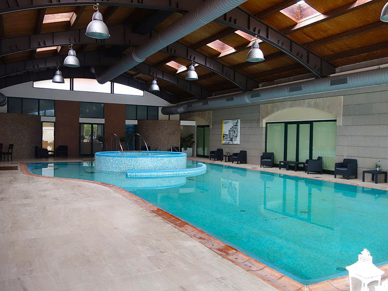 Piscina coperta con travi a vista e ampie vetrate